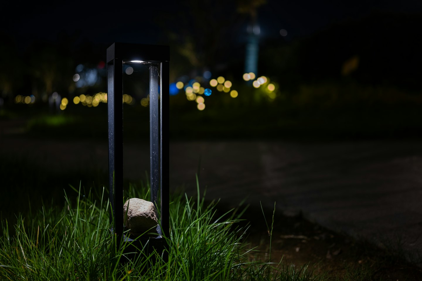 Außenlampe beleuchtet nachts grünes Gras und einen Stein.