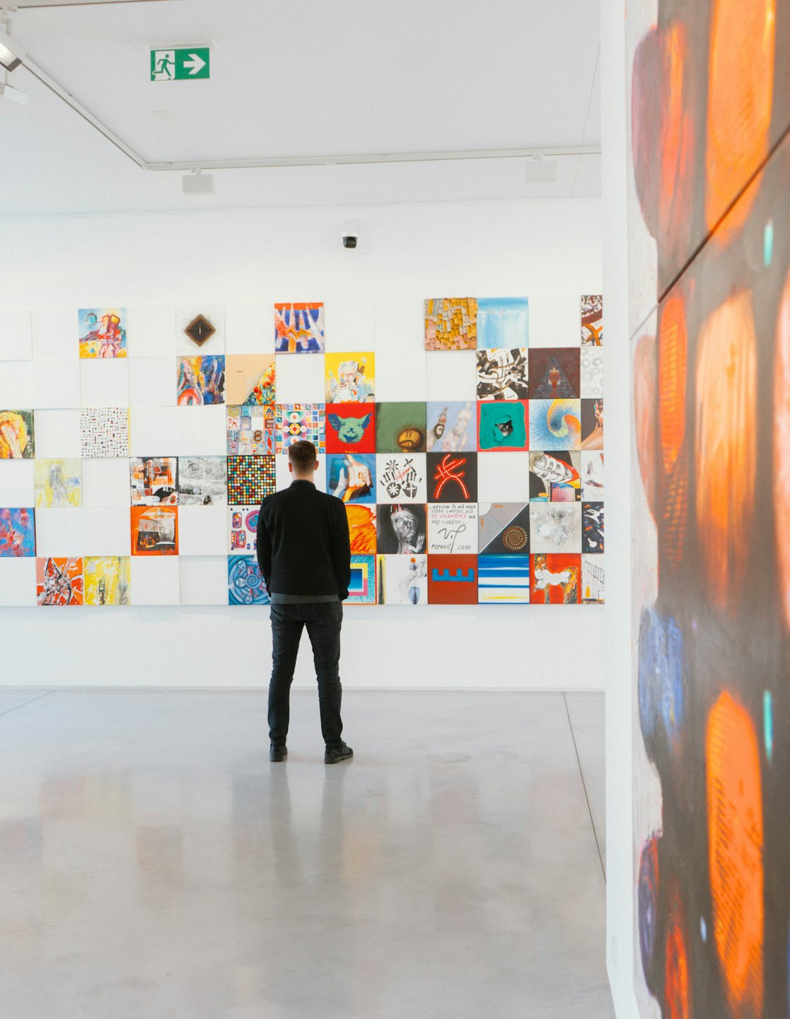 Person betrachtet diverse Kunstwerke in einer modernen Galerie.